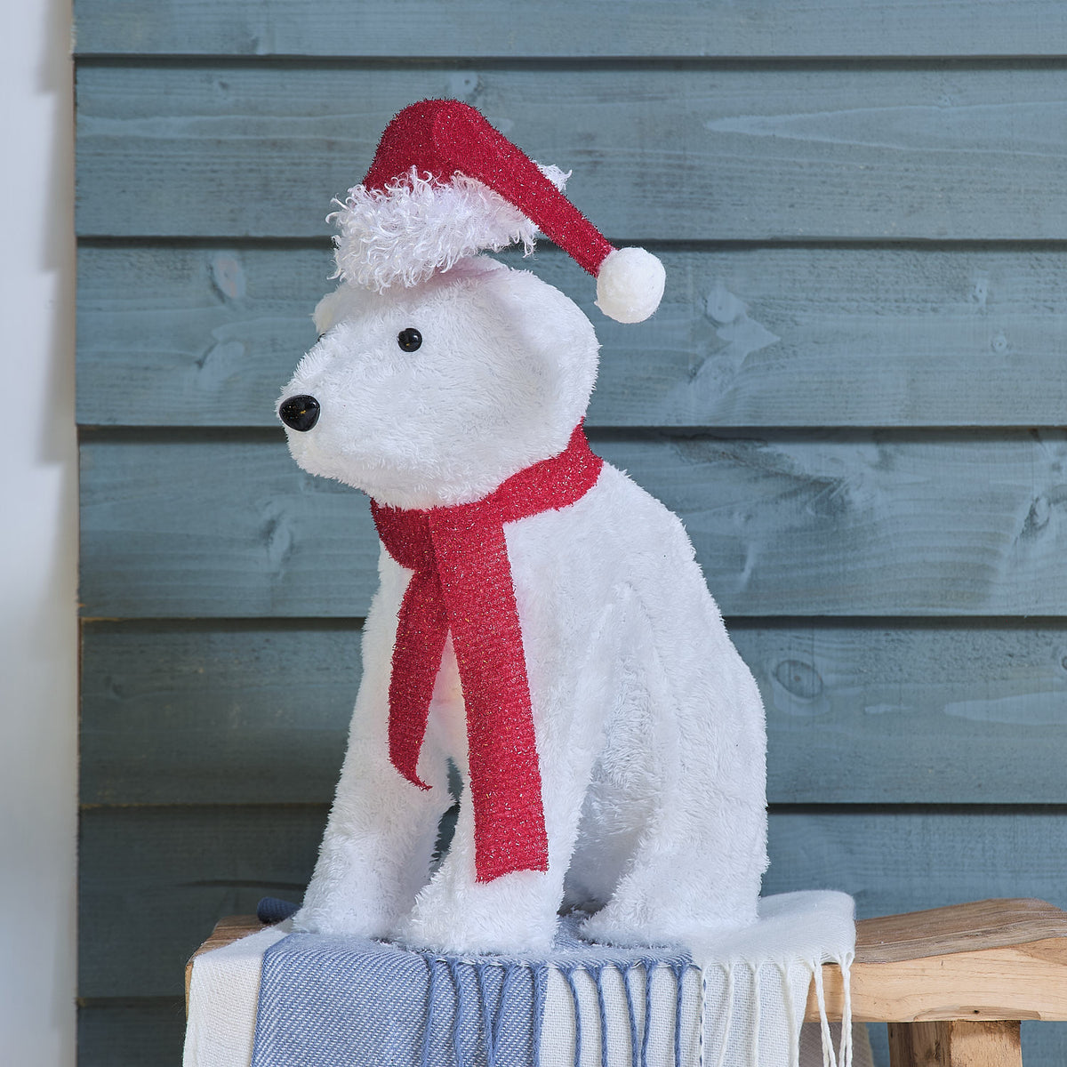 Une figurine illuminée d'un ours blanc portant un bonnet rouge et une écharpe rouge.